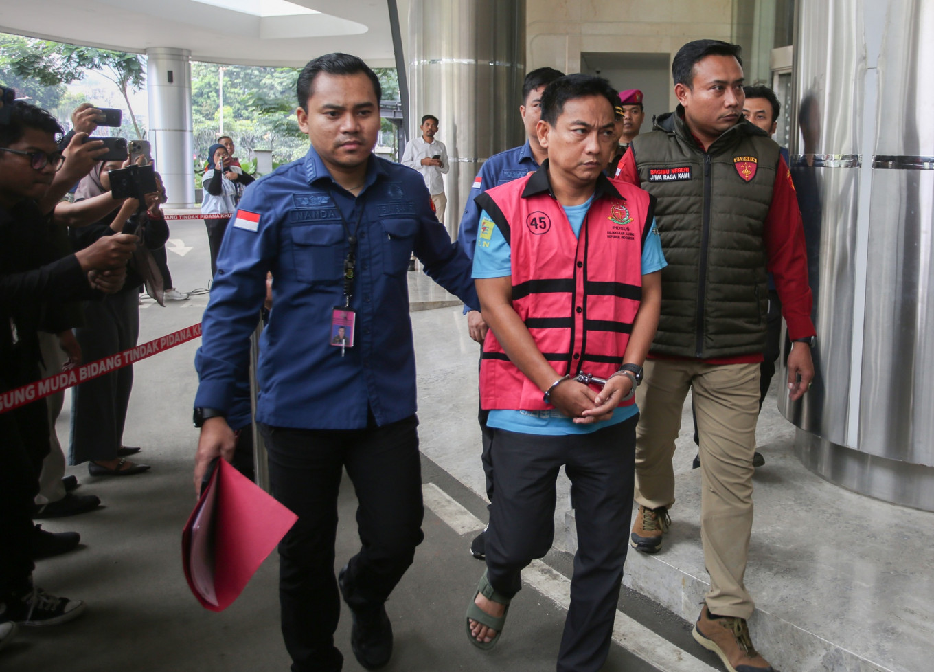 Attorney General's Office (AGO) investigators escort Indonesian Ombudsman chair Hery Susanto (second right) after an interrogation session at AGO's building in Jakarta on April 16, 2026. AGO named Hery a graft suspect for allegedly accepting a bribe pertaining to a nontax state revenue (PNBP) assessment for a nickel company.