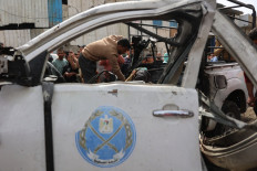 A Palestinian inspects the remains of a police vehicle destroyed in an Israeli strike that killed several people in Gaza City on April 14, 2026. The United Nations on April 10 condemned 'unrelenting' new killings of Palestinians in the Gaza Strip, six months into a fragile ceasefire between Israel and Hamas, with the health ministry in Gaza stating that the overall death toll since the war broke out on Oct. 7, 2023, now stands at 72,336 on April 14, 2026.