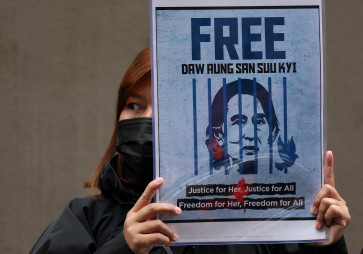 A Myanmar protester living in Japan holds a placard of Myanmar's detained former leader, Aung San Suu Kyi, during a rally denouncing an upcoming election led by the military junta outside Myanmar's embassy in Tokyo, Japan, on Dec. 14, 2025.