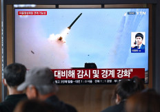 People watch a television screen showing a news broadcast with file footage of a North Korean missile test, at a train station in Seoul on April 19, 2026. North Korea test-fired multiple ballistic missiles on April 19, South Korea's military said, the latest in a recent flurry of launches by the nuclear-armed state.