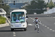 A robot and its engineers take part in the second Beijing E-Town Half Marathon and Humanoid Half Marathon in Beijing on April 19, 2026. 