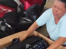 The mother of Reza Valentino Simamora is crying in this still picture taken from a video when opening a box on April 15 containing the suitcase of his son, who died in a work accident on a fishing vessel in South Korea, in Deli Serdang, North Sumatra. Reza went missing from a fishing vessel on Sept. 23, 2025, and was found dead four days later.