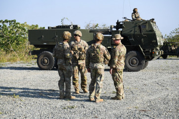 US soldiers stand next to one of their High Mobility Artillery Rocket System (HIMARS) prior to a live fire exercise during a joint exercise between the Philippines and the US at Fort Magsaysay, in the Philippines' Nueva Ecija province north of Manila on April 16, 2026.