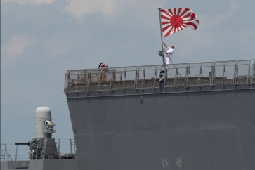 A sailor raises the Japan Maritime Self-Defense Force ensign on board the JS Ise, a Hyuga-class helicopter destroyer, as it docks at the international port in Manila on June 21, 2025. Japan's top government spokesman Minoru Kihara said on April 21, 2026, that Tokyo would ease decades-old arms export rules, paving the way for the sale of lethal weapons overseas.