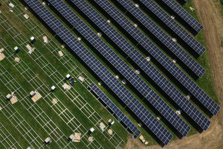 An aerial photograph taken on August 1, 2024 shows workers lifting solar panels onto their frames at a solar farm under construction on old farmland near Tetsworth, Oxfordshire, west of London, on August 1, 2024. The solar farm will generate 49.99 megawatts of electricity, enough to power around 15,00 homes.