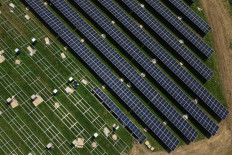 An aerial photograph taken on August 1, 2024 shows workers lifting solar panels onto their frames at a solar farm under construction on old farmland near Tetsworth, Oxfordshire, west of London, on August 1, 2024. The solar farm will generate 49.99 megawatts of electricity, enough to power around 15,00 homes.