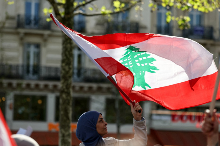 A protester waves a Lebanese national flag during a rally in support of Lebanon at Place de la Republique in central Paris on April 19, 2026. Israel and Lebanon agreed to a 10-day ceasefire on April 16 to allow for negotiations to end six weeks of war between Israel and the Iran-backed group Hezbollah that killed nearly 2,300 people since it began on March 2.