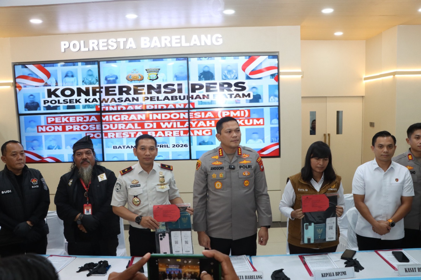 Batam, Rempang and Galang (Barelang) City Police chief Sr. Comr. Anggoro Wicaksono (center) is flanked by Batam Immigration Office head Wahyu Eka Putra (third left) and Batam Indonesian Migrant Workers Protection Service Post (P4MI) head Indah Wulandari Situmeang (third right) on April 20, 2026, during a press conference on preventing the departues of 43 illegal migrant workers to Malaysia at Barelang City Police headquarters in Batam, Riau Islands. The police have named two suspects in the case.