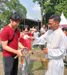 Pastor Marselinus Wisnu Wardana (right) of the Santo Andreas Parish Church blesses a turtle on April 18, 2026, with holy water during a ceremony at Bumi Maria Sareng Para Rasul Prayer Park in Bogor, West Java.