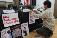 An activist puts up posters including one reading &ldquo;Acknowledge the 1998 mass rapes&ldquo; on April 22 ahead of a press briefing at the National Commission on Violence Against Women (Komnas Perempuan) office in Jakarta.