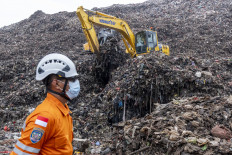 A rescue worker monitors an operation using heavy machinery to search for missing people on March 9, 2026, after a landslide buried trucks, food stalls and at least 13 people at the Bantar Gebang landfill in Bekasi, West Java.