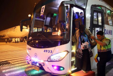 Ground staff (right) assist a pilgrim alighting from a bus  on April 22, 2026, at Kualanamu International Airport in Deli Serdang regency, North Sumatra. Medan Haj Embarkation saw off 360 pilgrims from the cities of Binjai and Medan as the first haj flight group from North Sumatra. 