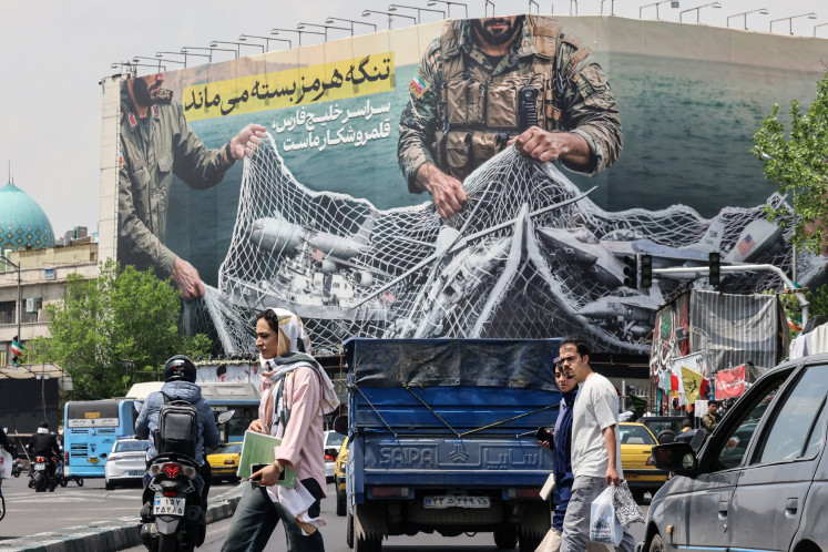Under the spotlight: Iranians walks past a giant billboard on April 22 reading &ldquo;The Strait of Hormuz remains closed&rdquo; at the Revolution Square in Tehran, amid a ceasefire in the region.