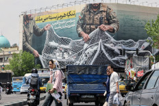 Under the spotlight: Iranians walks past a giant billboard on April 22 reading &ldquo;The Strait of Hormuz remains closed&rdquo; at the Revolution Square in Tehran, amid a ceasefire in the region.