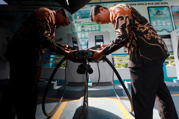A man charges an electric vehicle on April 21, 2026 at a public electric vehicle charging station in Banda Aceh, Aceh.