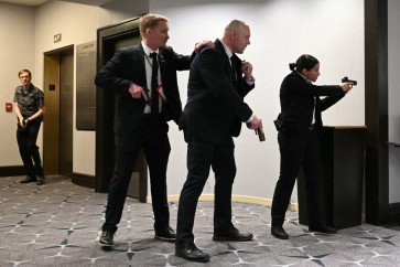 Agents draw their guns after loud bangs were heard during the White House Correspondents' dinner at the Washington Hilton in Washington, DC, on April 25, 2026. President Trump is attending the annual gala of the political press for the first time while in office.