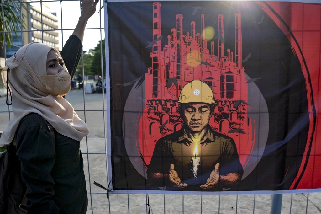 A worker takes part in an International Workers' Memorial Day vigil on April 28, 2025, to honor colleagues who have died from workplace accidents and occupational diseases, in an industrial area in Jakarta.