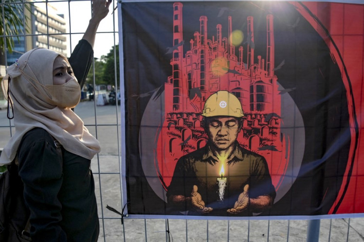 A worker takes part in an International Workers' Memorial Day vigil on April 28, 2025, to honor colleagues who have died from workplace accidents and occupational diseases, in an industrial area in Jakarta.