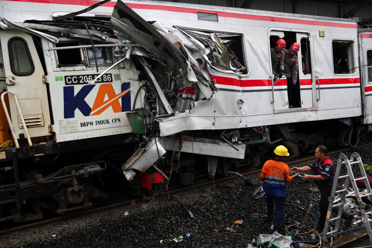 Technicians work on April 28, 2026, as police officers look on at the damaged commuter train site after a deadly collision between a Greater Jakarta commuter line train and an intercity train in Bekasi, West Java. At least 15 passengers died, and 88 others were injured in the crash on April 27. 