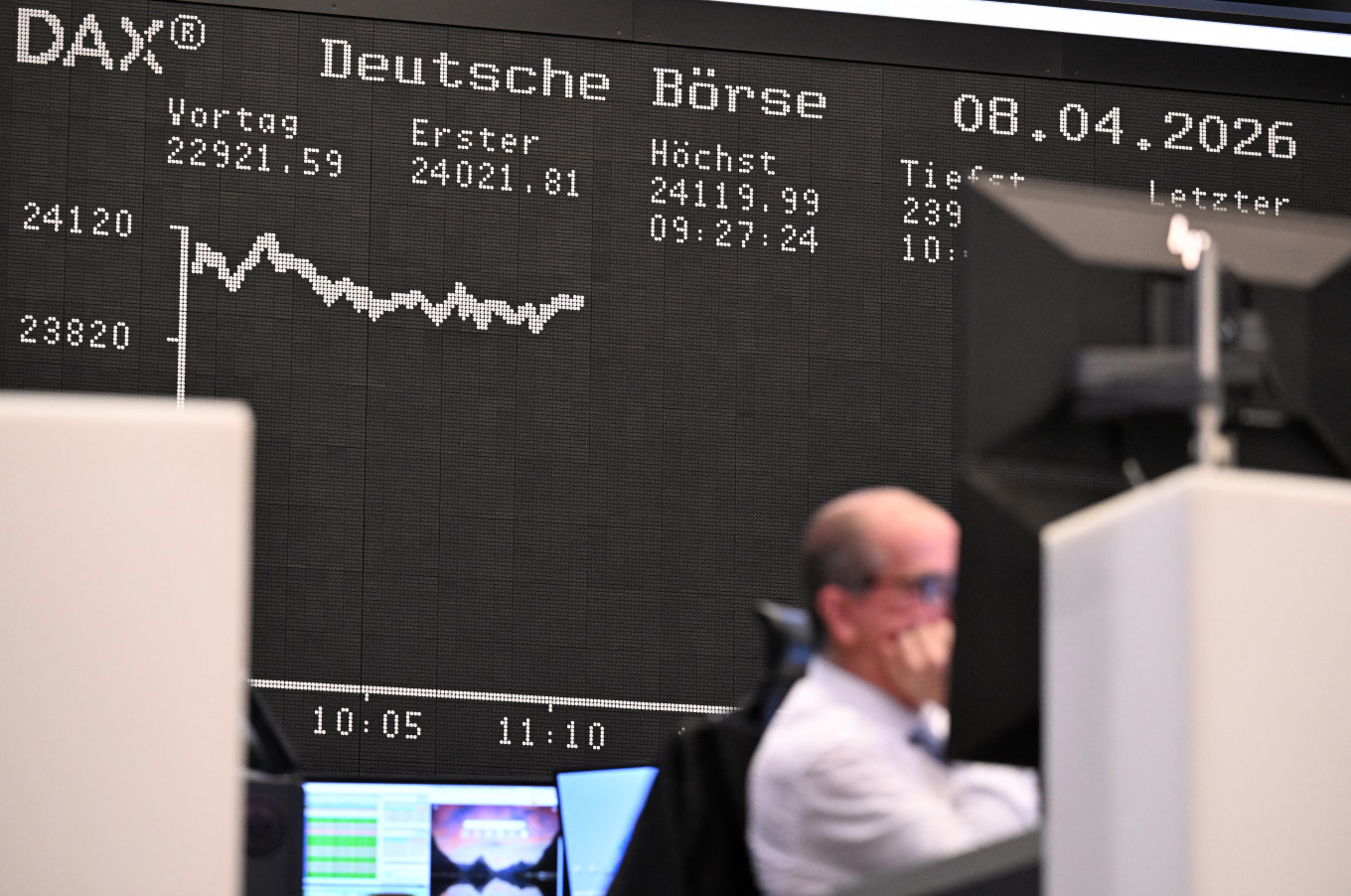 A trader works in front of a board displaying the chart of Germany's share index DAX on April 8, 2026, at the stock exchange in Frankfurt am Main, Germany.
