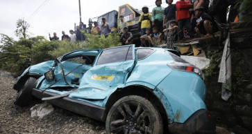 Onlookers inspect the remains of an EV taxi following a crash on April 27, 2026.