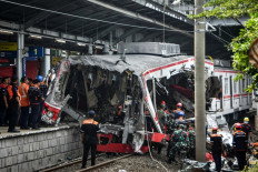 Workers clear debris at the train collision site after the locomotive of a passenger train pierced through the rear car of a commuter train at Bekasi Timur Station in Bekasi, West Java on April 28, 2026. President Prabowo Subianto ordered an investigation on April 28 after a long-distance train smashed into a stationary commuter train overnight, killing 15 people and injuring dozens. 