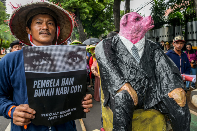 A man holding a sign reading 'Human rights defenders are not prophets! Strengthen Anti-SLAPP regulations' takes part in a rally on Dec. 10, 2024, commemorating the International Human Rights Day in Jakarta.