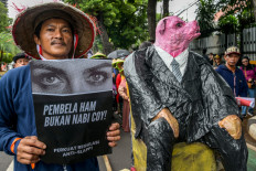 A man holding a sign reading 'Human rights defenders are not prophets! Strengthen Anti-SLAPP regulations' takes part in a rally on Dec. 10, 2024, commemorating the International Human Rights Day in Jakarta.