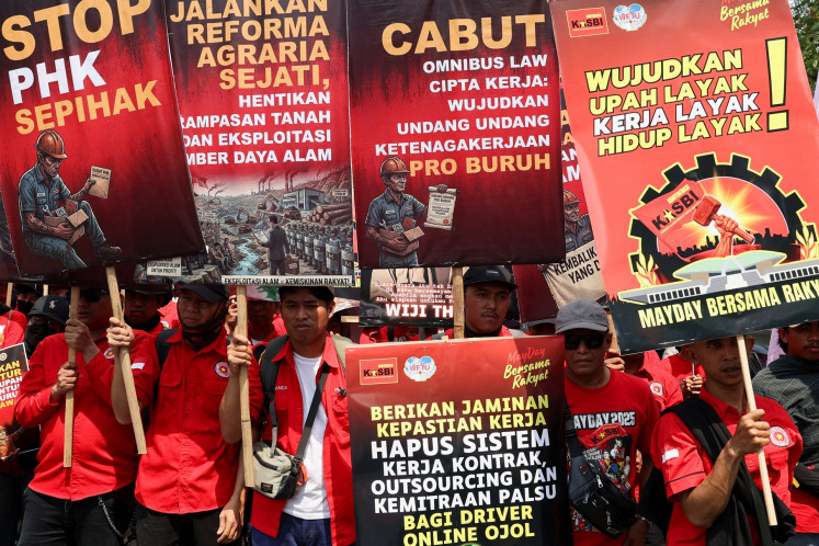 Laborers carry banners on Friday as they hold a Labor Day commemoration protest outside the Senayan Legislative Complex in Jakarta.