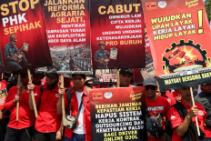 Laborers carry banners on Friday as they hold a Labor Day commemoration protest outside the Senayan Legislative Complex in Jakarta.
