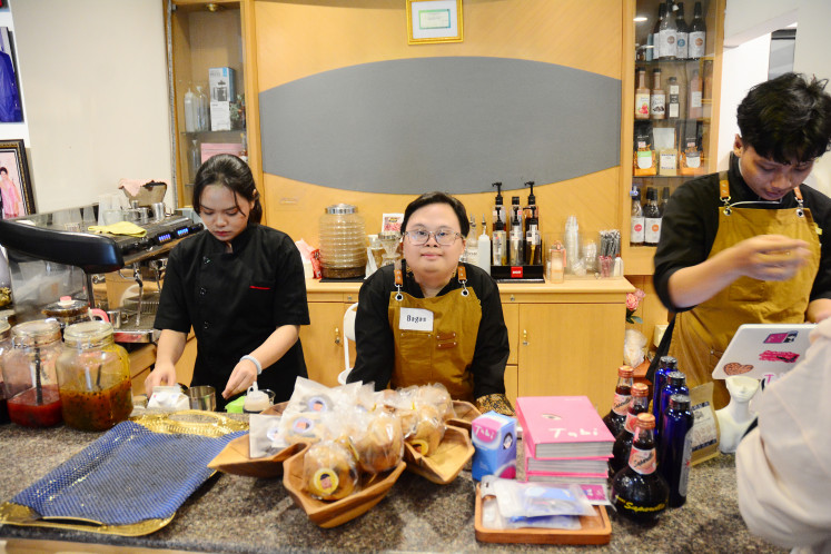 At your service: Bagas (center), a 19-year-old employee with Down syndrome, waits for orders at the counter of Kopi Kamu in South Jakarta on April 18, 2026. 