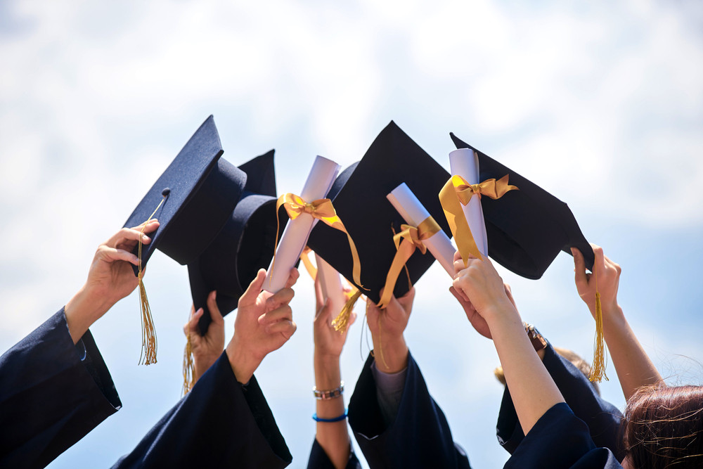 An llustration of graduates holding their caps and diplomas.