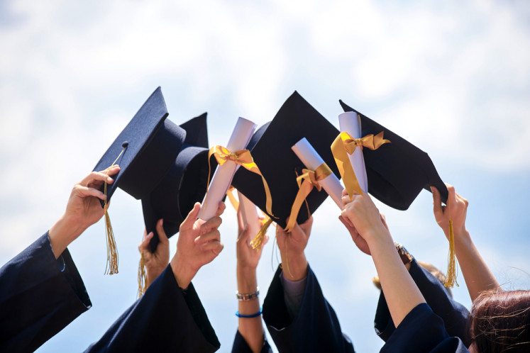 An llustration of graduates holding their caps and diplomas.