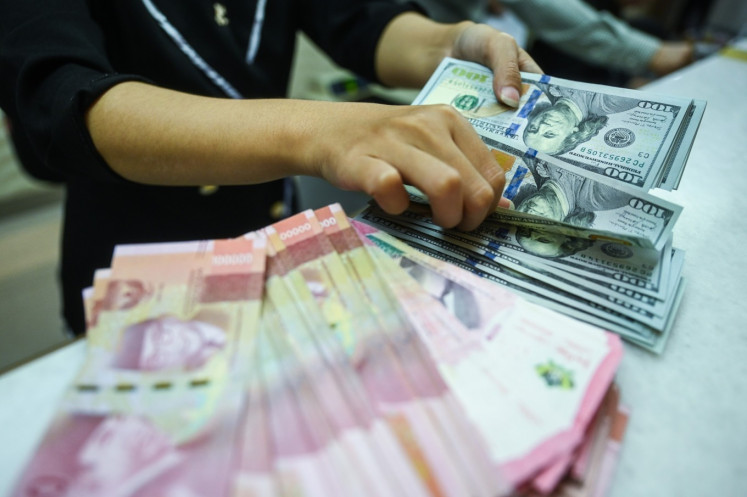 A clerk counts United States dollar banknotes on May 22, 2024, at a money changer in Jakarta. 