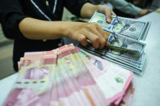 A clerk counts United States dollar banknotes on May 22, 2024, at a money changer in Jakarta. 