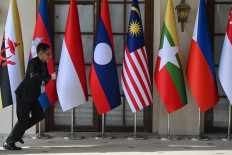 A man runs past national flags of ASEAN member states on May 5, 2026, outside a media center in Cebu, the Philippines, ahead of the 48th ASEAN Summit.