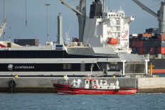 An ambulance boat carrying crew members wearing hazmat suits, returns to the port of Praia, the capital of Cape Verde, on May 5, 2026 after a visit to the cruise ship MV Hondius, while stationary off the harbor. Two seriously ill crew members on a cruise ship stricken by a deadly hantavirus outbreak will be evacuated via Cape Verde to the Netherlands, allowing the vessel to sail on to Spain's Canary Islands, the ship operator said on May 5, 2026.