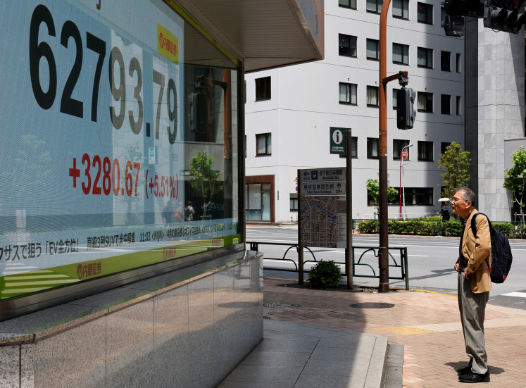 A pedestrian looks at a stock quotation board showing the Nikkei share average outside a brokerage in Tokyo on May 7, 2026.