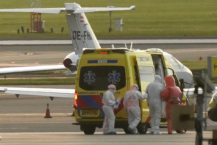 A person in a hazmat suit (second right) is escorted to an ambulance from a medical aircraft allegedly carrying some of the passengers from the cruise ship MV Hondius believed to be infected with hantavirus, at Schiphol airport near Amsterdam on May 6, 2026. A plane that left Cape Verde following the evacuation of a cruise ship hit by the hantavirus landed in Spain's Canary Islands on May 6, while a second flight headed for the Netherlands.