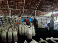 Plainclothes officers from the special criminal investigation unit inspect around 3,000 sacks of mangrove charcoal during a raid on an illicit charcoal factory in eastern Meranti Islands regency, in this undated handout photo provided by the Riau Police on May 6, 2026.