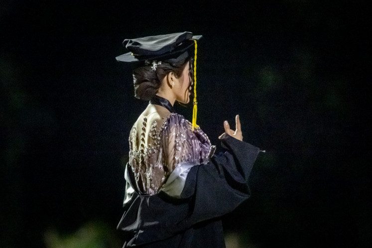 Ready to launch: A student of a private university poses in a graduation cap and gown a cap on Oct. 6, 2025, during a professional photo shoot at Banteng Square Park in Central Jakarta.

