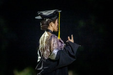 Ready to launch: A student of a private university poses in a graduation cap and gown a cap on Oct. 6, 2025, during a professional photo shoot at Banteng Square Park in Central Jakarta.


