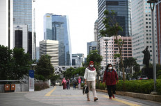Office workers and other pedestrians stroll along a sidewalk on April 16, 2020, along Jl. Sudirman in downtown Jakarta.