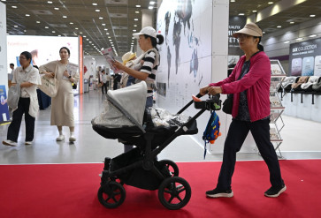 This picture taken on April 30, 2026 shows a woman pushing a stroller as she visits a baby fair in Seoul. South Korea has one of the world's lowest birth rates, and the government has spent billions of dollars trying to encourage citizens to have more babies and cushion the worst impacts of a shrinking population. The Asian nation is still nowhere near reversing the trend, but a modest baby bump is offering a glimmer of hope after years of bleak statistics.