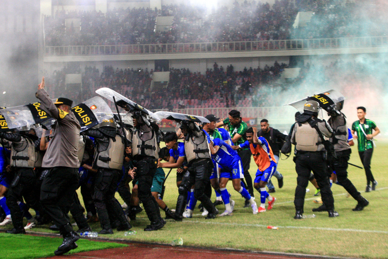 Police officers evacuate players and officials of Adhyaksa FC Banten during unrest following a playoff match against Persipura Jayapura in the 2025-2026 Pegadaian Championship, Indonesia&rsquo;s second-tier soccer league, at Lukas Enembe Stadium in Jayapura, Papua, on May 8, 2026. 