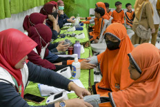 Healthcare workers examine elementary school students during the launch of a free health check programme for children, in Jakarta on August 4, 2025. 
