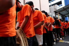 Foreign nationals, who police said were mainly from Vietnam, walk on May 10, 2026, ahead of being transported after their arrest in Jakarta. The detainees have been suspected of running an online gambling operation for two months at an office building