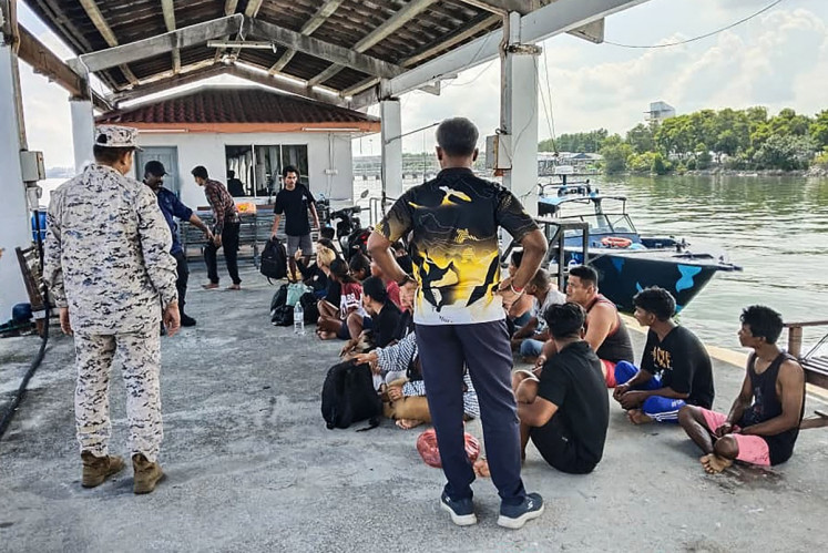 This handout picture taken and released by the Malaysian Maritime Enforcement Agency (MMEA) on May 12, 2026 shows a MMEA staff member (left) checking on survivors rescued during a search and rescue operation off the coast of Pangkor Island in Perak, after a boat carrying migrants capsized. A boat carrying 37 undocumented migrants believed to be from Indonesia sank off Pangkor island on Malaysia's west coast, leaving 14 people still missing, maritime authorities said.