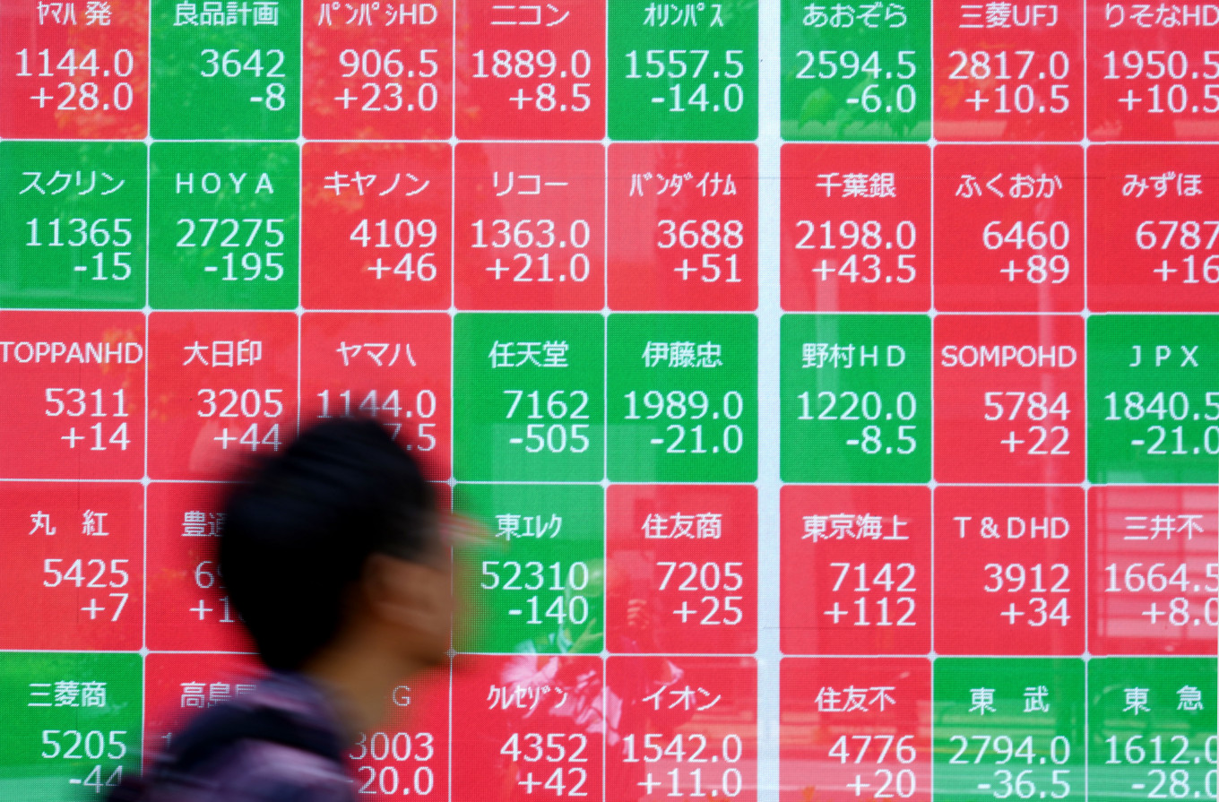 A man walks past an electronic quotation board displaying the Nikkei 225 stock prices on the Tokyo Stock Exchange along a street in Tokyo on May 11, 2026.