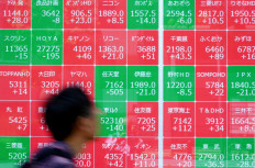 A man walks past an electronic quotation board displaying the Nikkei 225 stock prices on the Tokyo Stock Exchange along a street in Tokyo on May 11, 2026.